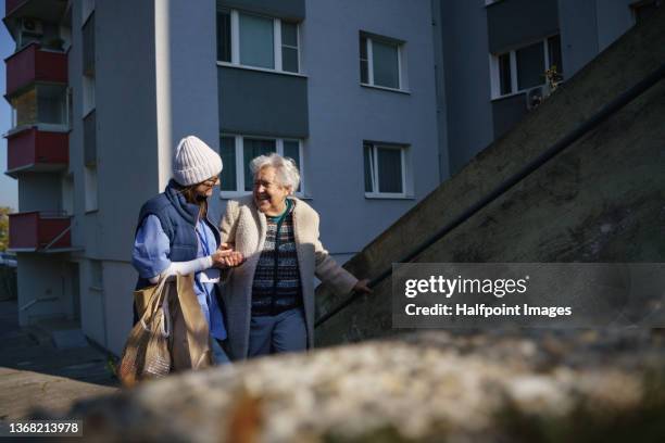 senior woman and caregiver outdoors on a walk in town, laughing. - carrying photos et images de collection