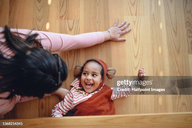 top view of little multiracial boy in costume hiding under coffee table and playing with mother. - kid hide and seek stock pictures, royalty-free photos & images