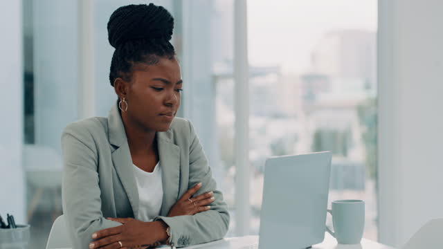 그녀의 사무실에 혼자 앉아 그녀의 노트북을 사용하는 동안 스트레스를 느끼는 매력적인 젊은 사업가의 4K 비디오 영상