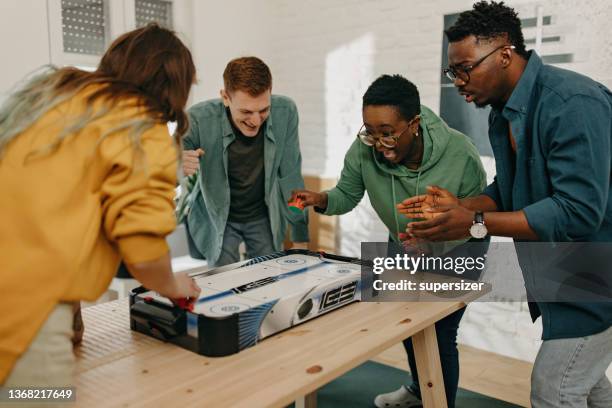 eine gruppe von freunden spielt airhockey und hat spaß - opposition party stock-fotos und bilder