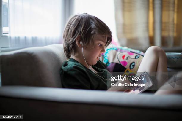 boy with headphones using digital tablet in living room - child listening differential focus stock pictures, royalty-free photos & images