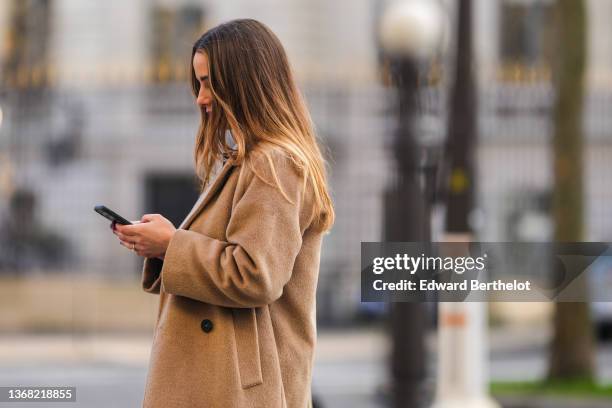 Maria Rosaria Rizzo wears a dark purple high neck pullover, a beige long coat, during a street style fashion photo session, on January 13, 2022 in...