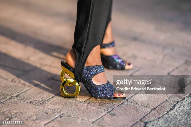 Carrole Sagba @linaose wears black legging pants from Vila, black glitter / sequined strappy with gold wavy heels sandals from Dear Frances, during a...