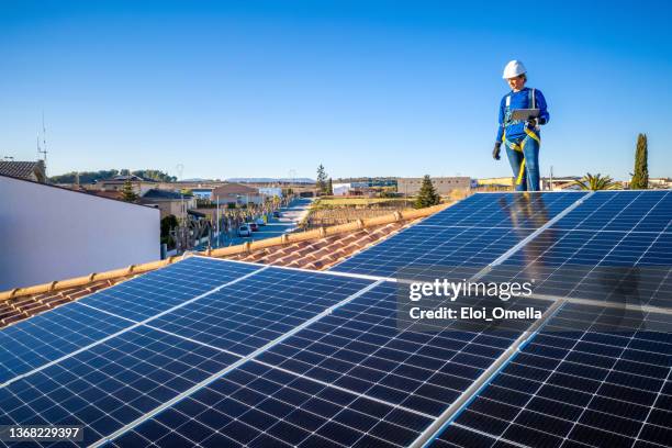 technician woman working on maintenance of solar photovoltaic panel installed on domestic home rooftop with a tablet - safety harness stock pictures, royalty-free photos & images