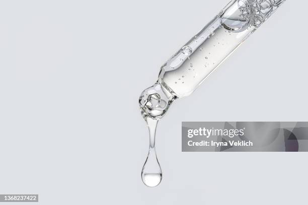 close-up pipette with face serum or essential oil with oxygen aqua bubbles on grey color background. - laboratory equipment stock-fotos und bilder