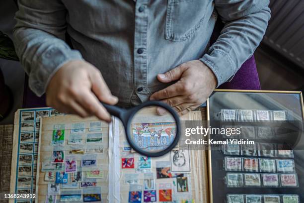 senior man colleziona francobolli da tutto il mondo - collezionare francobolli foto e immagini stock