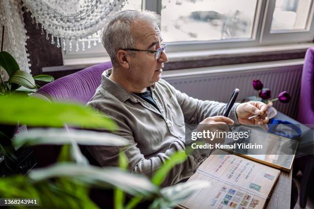 senior man colleziona francobolli da tutto il mondo - collezionare francobolli foto e immagini stock