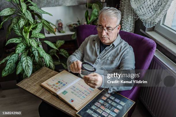 senior man collecting stamps from around the world - stamp collection stock pictures, royalty-free photos & images