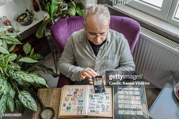 senior man colleziona francobolli da tutto il mondo - collezionare francobolli foto e immagini stock