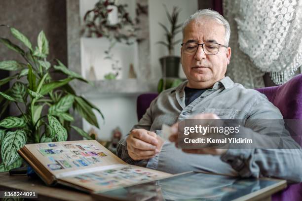 senior man colleziona francobolli da tutto il mondo - collezionare francobolli foto e immagini stock