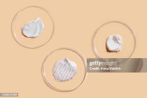 smears of beauty product white gel and cosmetic cream in petri dish on pastel beige color background. - boîte de pétri photos et images de collection
