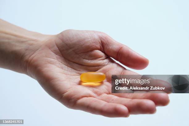 a woman holds omega-3 fish oil capsules in the palm of her hand or in her hand. healthy lifestyle, prevention and treatment of diseases. the girl takes and drinks dietary supplements and vitamins. biologically active additive. intake of healthy fats. - fish oil foto e immagini stock