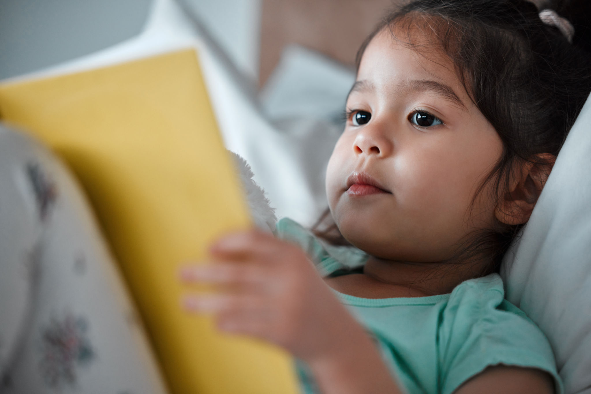Shot of a little girl reading a book while lying on her bed Shot of a little girl reading a book while lying on her bed