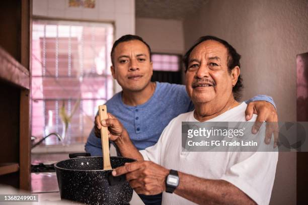 portrait of a latin father and son cooking at home - fathers day dinner stock pictures, royalty-free photos & images