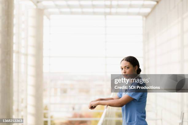 serious female surgeon takes break in hospital atrium - atrium stock pictures, royalty-free photos & images