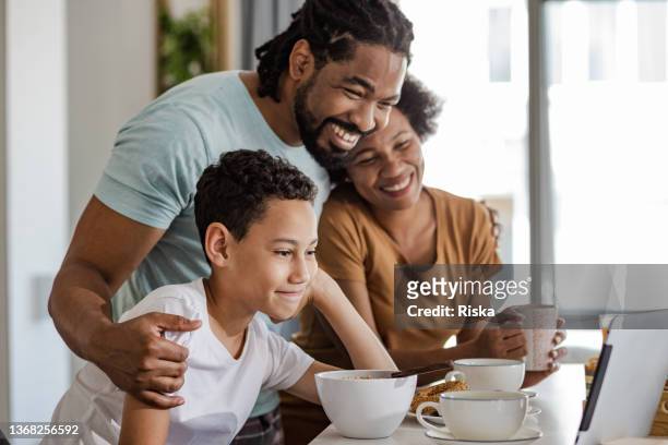 familie frühstückt zusammen und spricht online mit ihren freunden - boy in pajamas and mom on tablet stock-fotos und bilder