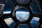 Cupola porthole on ISS orbital station. International space station. Orbit and deep space with stars view from porthole. Spaceship and blue planet. People in sapce. Elements of this image furnished by NASA