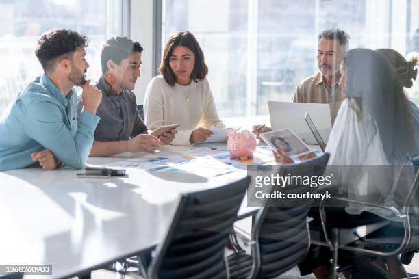 multi racial group of business people with a piggy bank. there are people of different ethnic groups. - different loans stockfoto's en -beelden