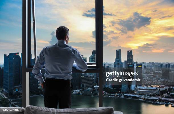 businessman watching the city view in his office at sunset - singapore port stock pictures, royalty-free photos & images