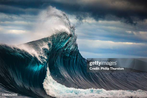 tall powerful cross ocean wave breaking during a dark, stormy evening. - golf stockfoto's en -beelden
