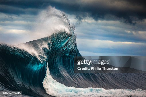 Tall powerful cross ocean wave breaking during a dark, stormy evening. Tall powerful cross ocean wave breaking during a dark, stormy evening.