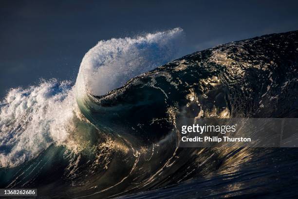 beautiful close up of crashing dark ocean wave in golden light - perfect storm stock pictures, royalty-free photos & images