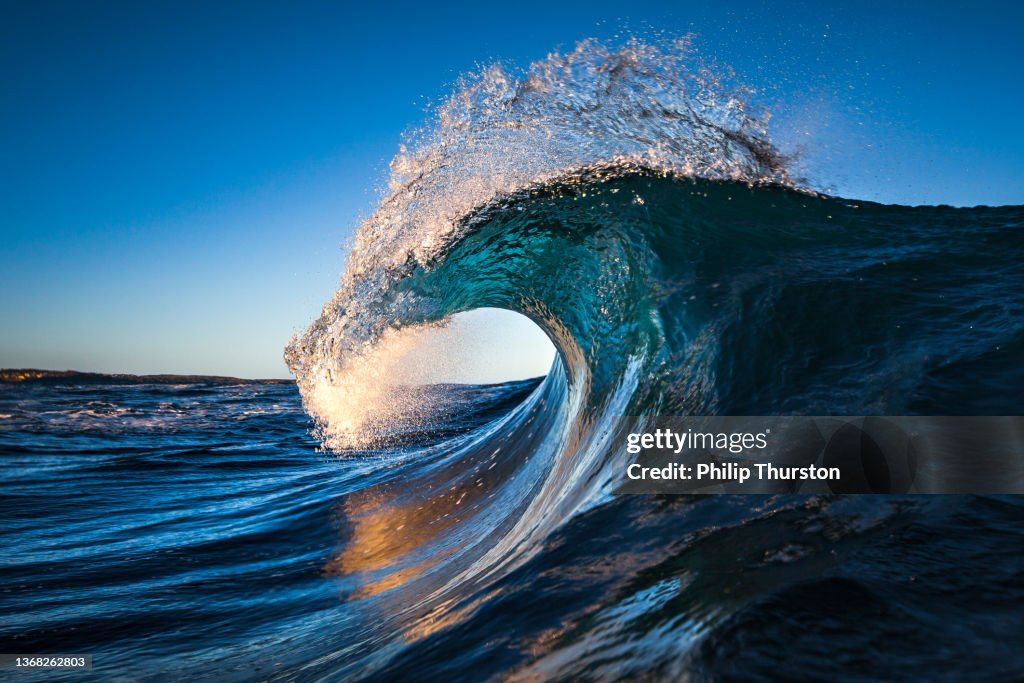 Onda do oceano azul cresting na luz da manhã