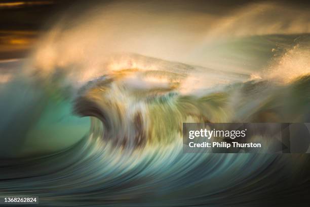 blurred motion of blue ocean wave crashing in golden light - streak bildbanksfoton och bilder