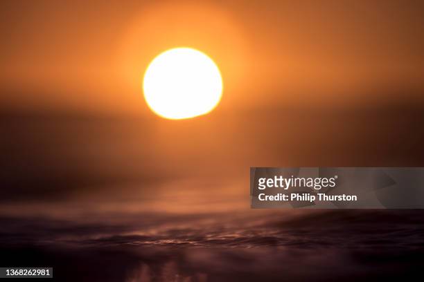 helle goldene sonne, die hinter dem ozeanhorizont untergeht - australia summer reflection stock-fotos und bilder