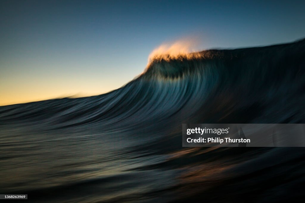 Dark majestic wave cresting in golden morning light
