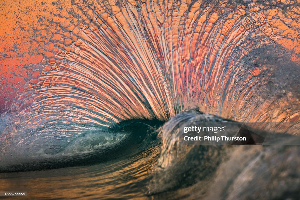 Magnificent spray shape formed by waves colliding in front of bright pink sky