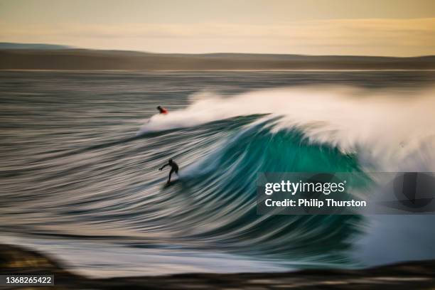 langsamer verschluss von surfern, die eine perfekte blaugrüne welle reiten - in the surf stock-fotos und bilder