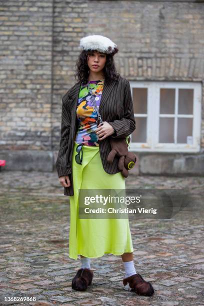 Guest is seen wearing hat, striped blazer, neon skirt, brown teddy bag outside Stine Goya during Copenhagen Fashion Week Autumn/Winter 2022 on...