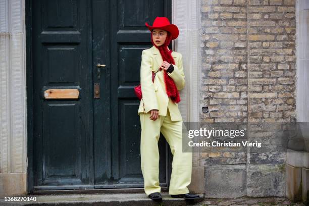 Emma Friedsell seen wearing yellow suit, red cowboy hat, scarf, bag outside Stine Goya during Copenhagen Fashion Week Autumn/Winter 2022 on February...