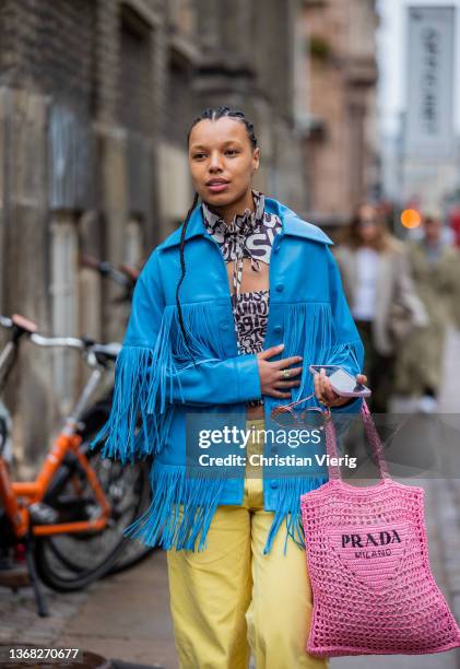 Guest is seen wearing blue jacket with fringes, yellow pants, pink Prada bag outside Stine Goya during Copenhagen Fashion Week Autumn/Winter 2022 on...