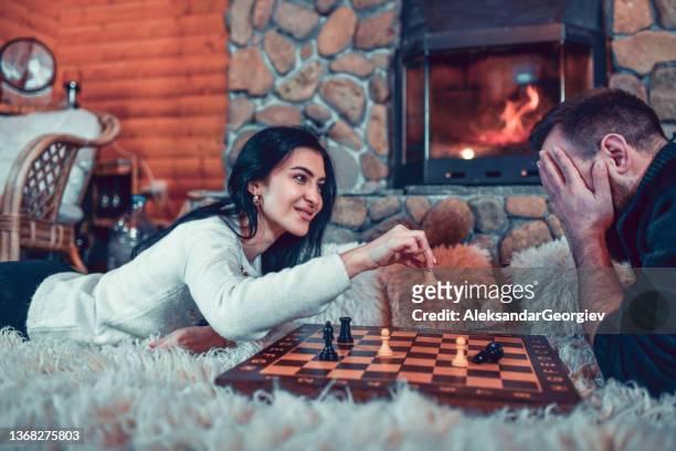 männlich bekommt check mate von freundin beim entspannen am cottage kamin - schach matt stock-fotos und bilder