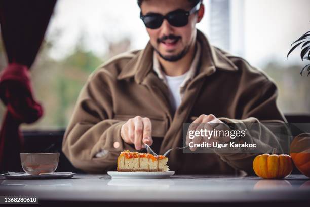 man drinking coffee and eating cheese cake at cafe - man eating pie stock pictures, royalty-free photos & images