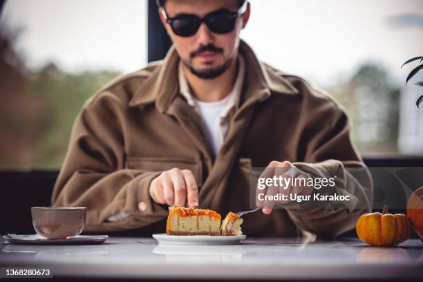 man drinking coffee and eating cheese cake at cafe - man eating pie stock pictures, royalty-free photos & images