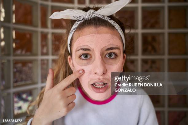 young caucasian teenager applying facial treatment cream reflecting on a mirror. healthcare and medicine concept. - spain teen face bildbanksfoton och bilder