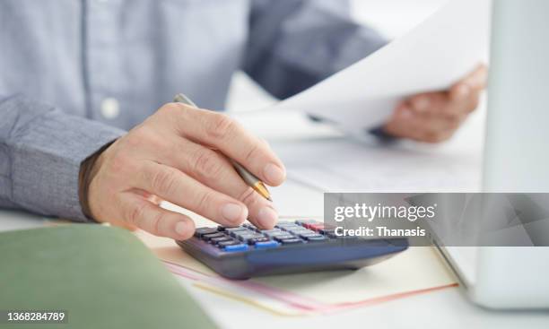 an accountant analyzing a tax form chart with a calculator - bookkeeping computer stock pictures, royalty-free photos & images