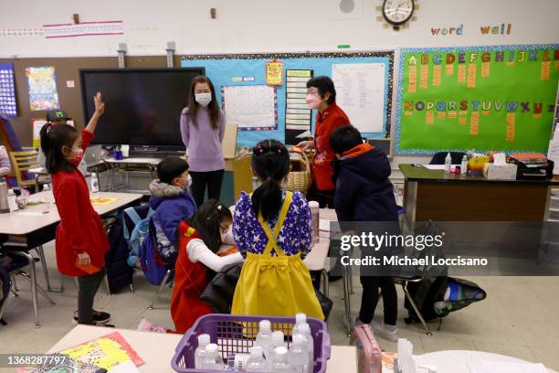 Taking a break from handing out red envelopes and candy in a cultural celebration of the Lunar New Year, Principal Alice Hom talks with schoolteacher...