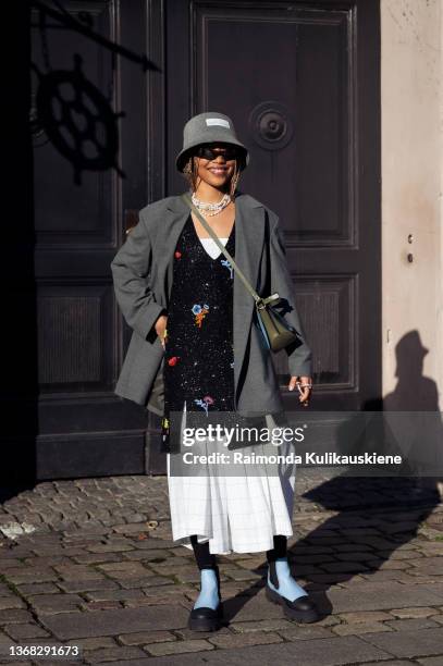 Petra Henriette Rufi wearing long white dress, black vest with embroidery, grey coat, grey bucket hat and Ganni bag wearing outside A. Roege Hove in...