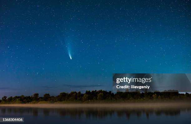 cometa nel cielo notturno. cielo stellato estivo. stelle nel cielo. bellissimo paesaggio notturno. lunga esposizione. fotografia concettuale. nebbia sull'acqua. paesaggio atmosferico. crepuscolo mattutino. cometa neowise - comite foto e immagini stock