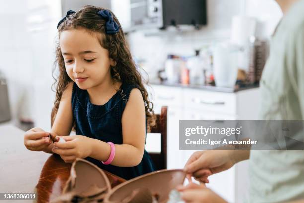 little girl eating easter egg in the kitchen - open day 10 stockfoto's en -beelden