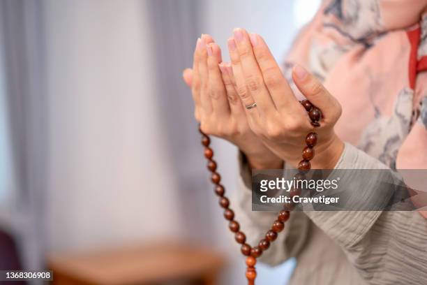 cropped shot of muslim woman praying post at home . - holy quran - fotografias e filmes do acervo
