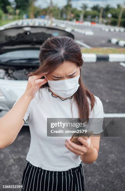 young asian woman wearing protective face mask and using smart phone asking for assistance near her car broken down on the road side - overheated stock pictures, royalty-free photos & images