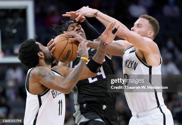 Buddy Hield of the Sacramento Kings has his shot blocked by Kyrie Irving and Blake Griffin of the Brooklyn Nets at the end of the first quarter of...