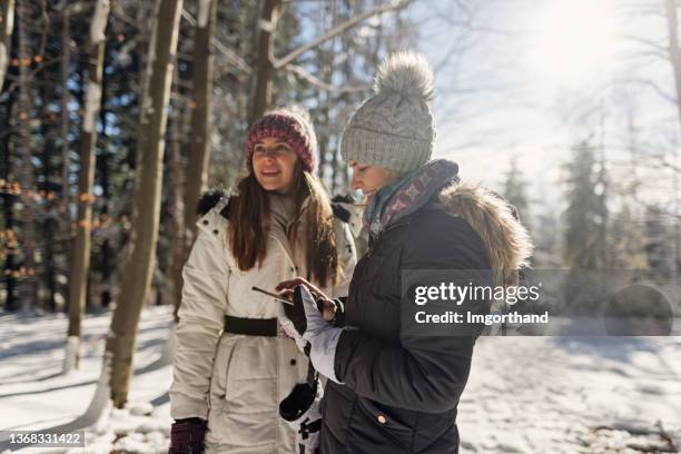 mother and daughter checking social media in beautiful winter forest. - mother media call stock pictures, royalty-free photos & images