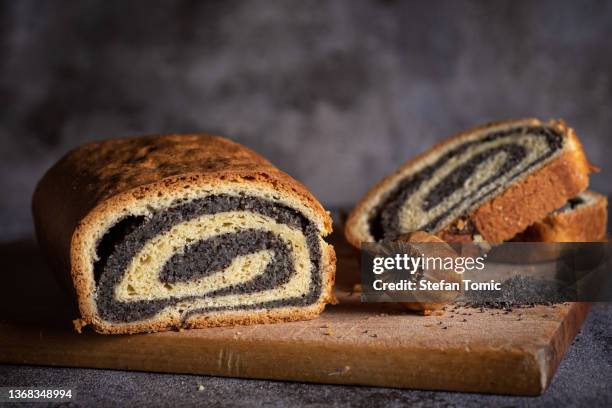 rouleau sucré de strudel aux graines de pavot tranché sur une planche rustique - graine de pavot photos et images de collection