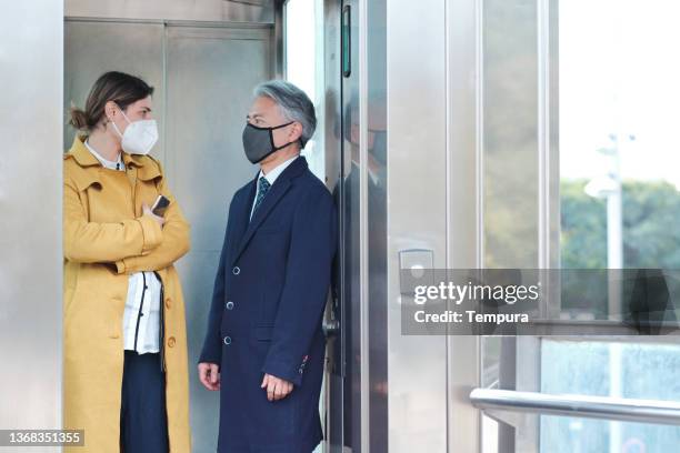 two businesspeople meet on the elevator. - social distancing elevator stock pictures, royalty-free photos & images
